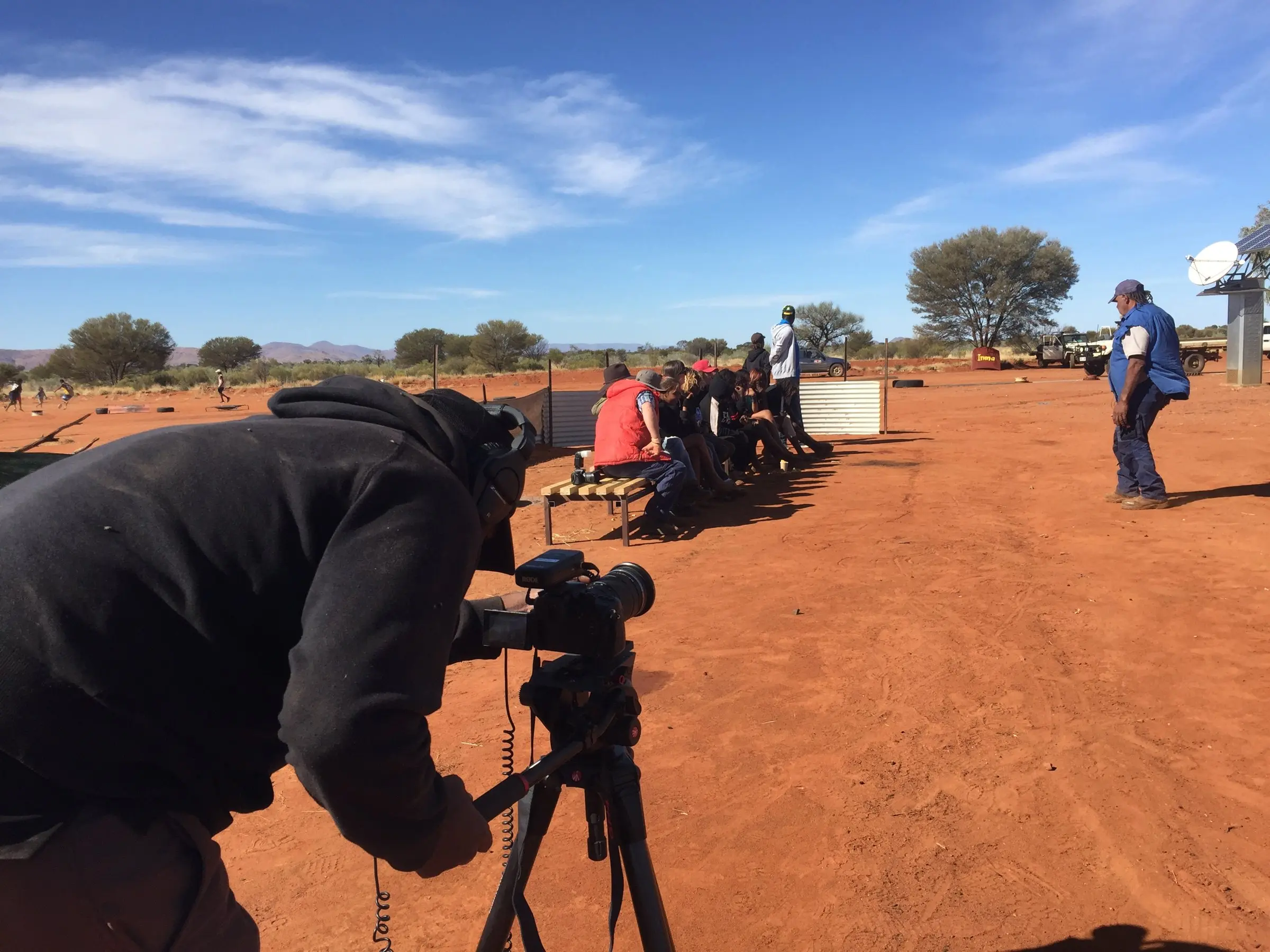 Camera operator with a tripod on red earth